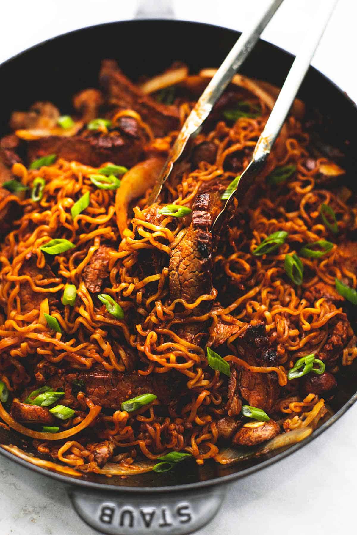 One Pan Spicy Korean Beef Noodles | lecremedelacrumb.com spicy Korean beef noodles with tongs in a skillet.