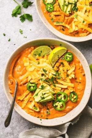overhead view of enchilada soup in bowl with lime wedge and jalapeno slices